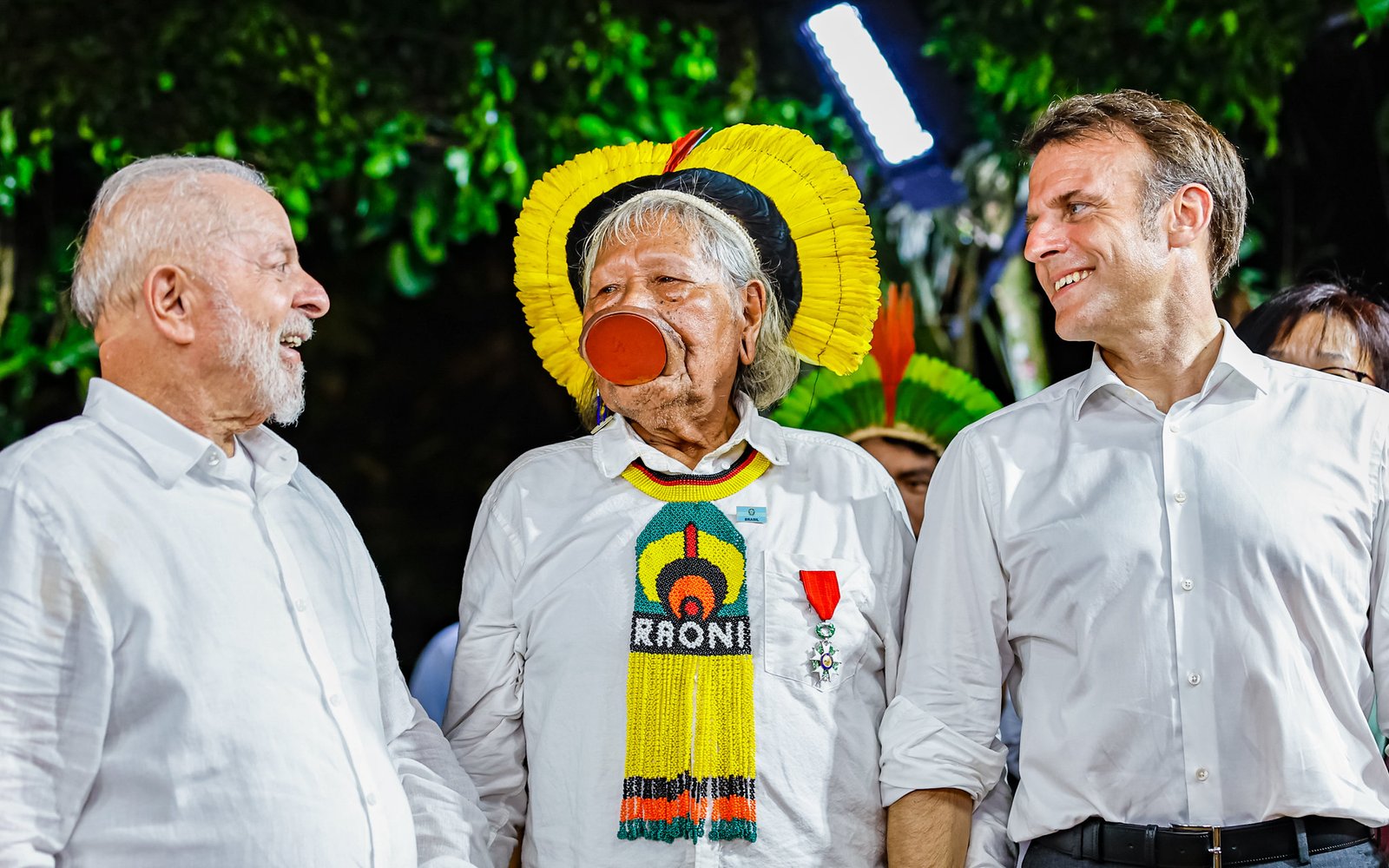 Lula e Macron trocam sorrisos —com cacique Raoni ao centro. Crédito: PR, divulgação