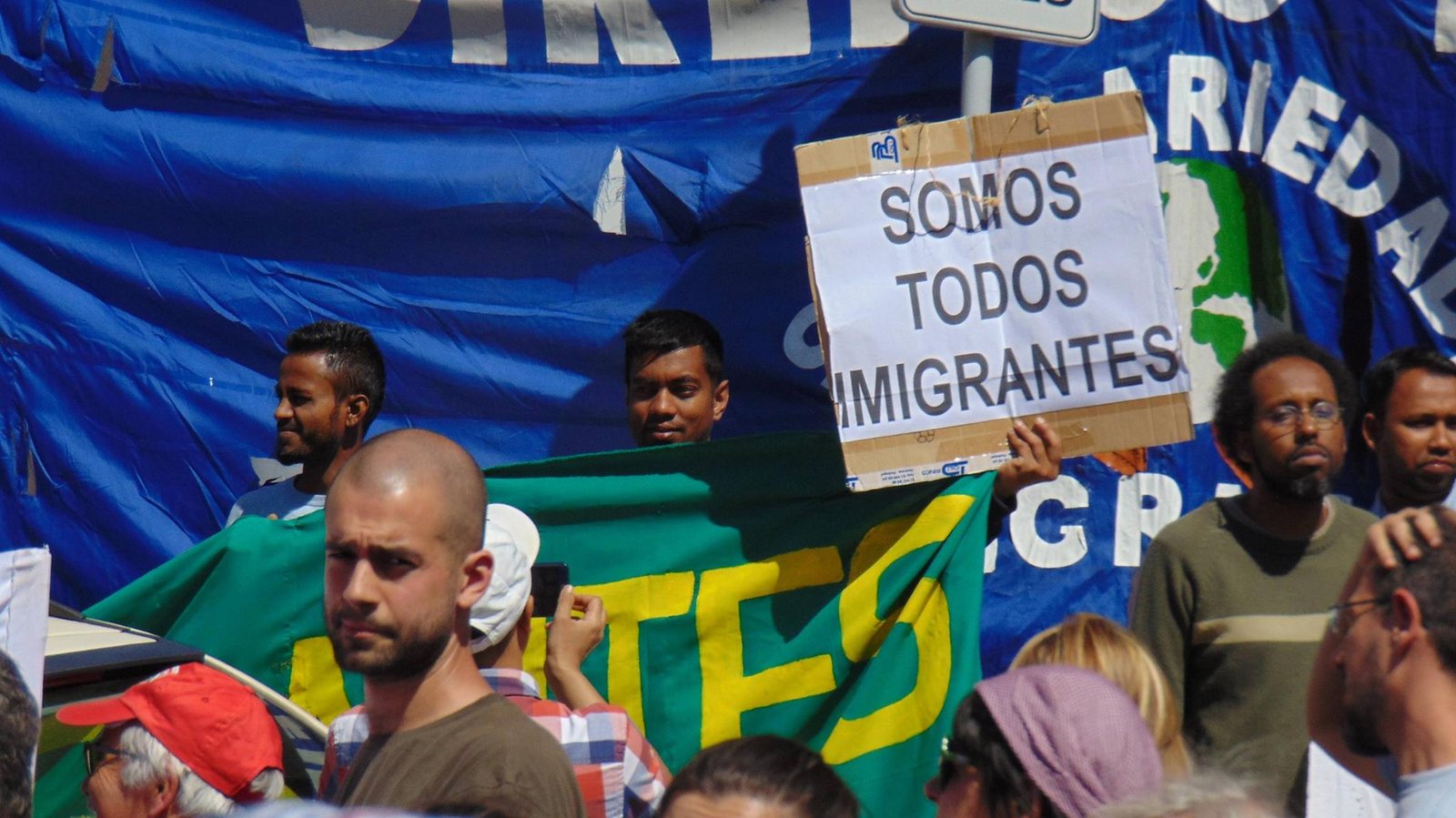 Rapaz ergue cartaz com o dizer "Somos todos imigrantes" durante protesto. Crédito: Solidariedade Imigrante, Reprodução Facebook